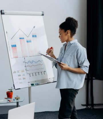 Professional businesswoman presenting data analytics on a flipchart in a modern office.